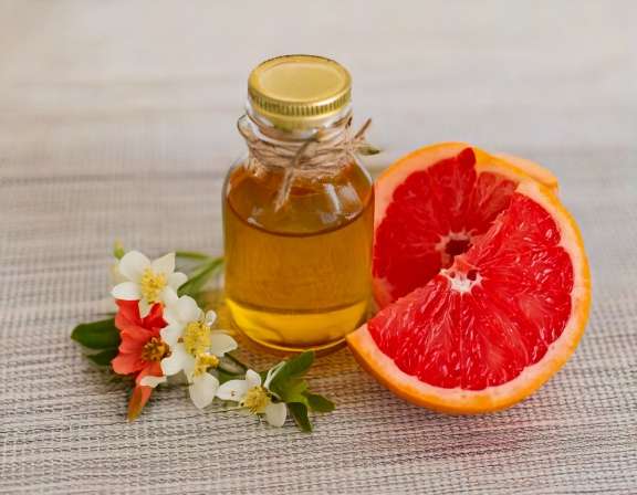 firefly generate an image of grapefruit essential oil and a jar with flowers; concept for sel 217485